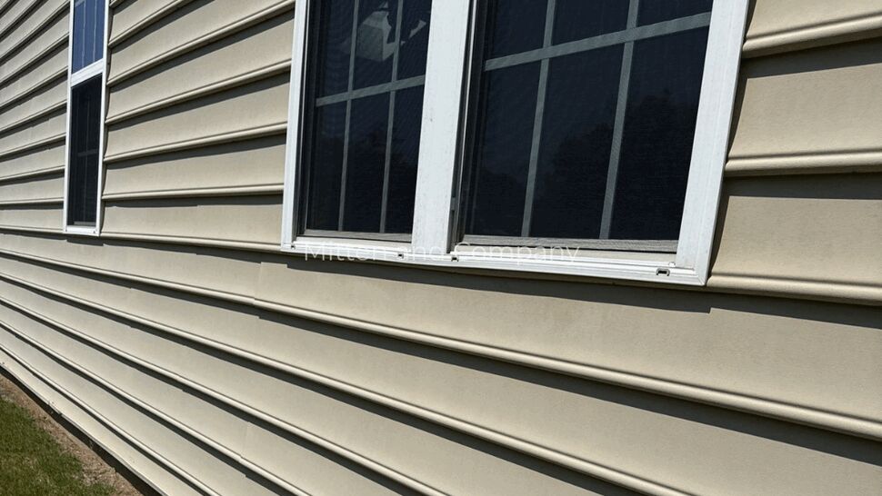 Beige Vinyl Siding with Windows | Mitten & Company Close-up of beige vinyl siding and two white-framed windows on a home's exterior.