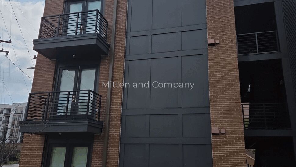 Brick Multifamily Building Exterior | Mitten & Company Three-story brick multifamily building with black metal balconies and parapet.