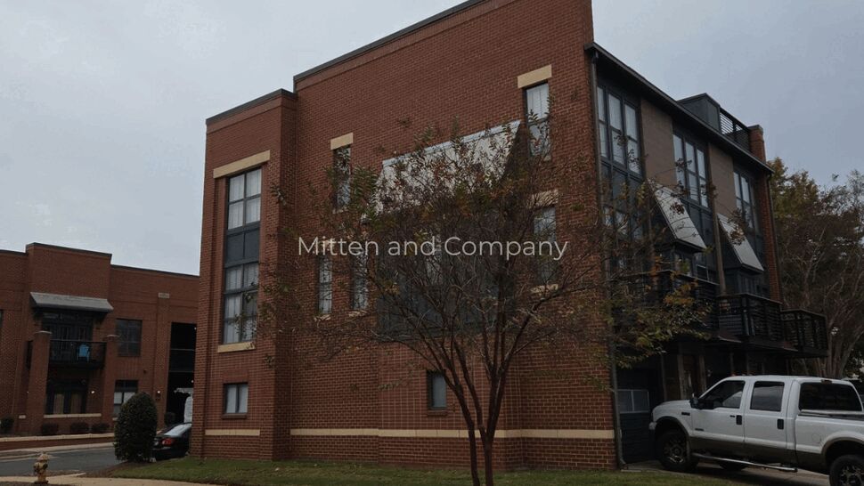 Brick Multifamily Exterior | Mitten & Company Brick three-story multifamily building exterior with small tree and parked truck.