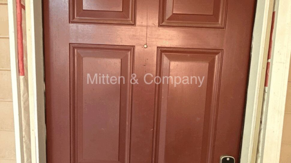 Close-up of red entry door with peephole, deadbolt and smart lock.