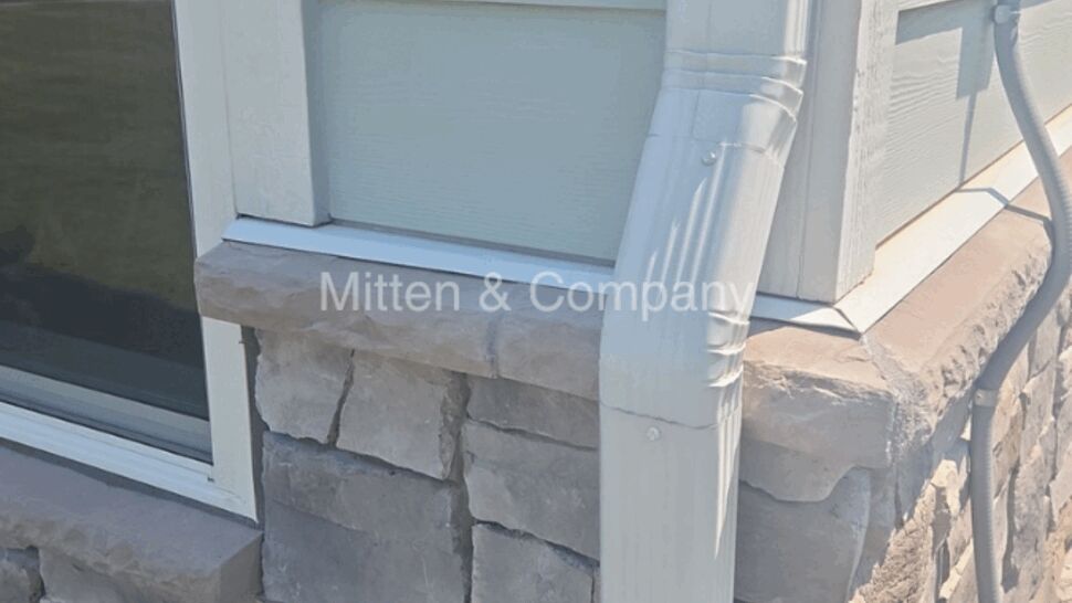 Corner window with stone veneer and vertical downspout