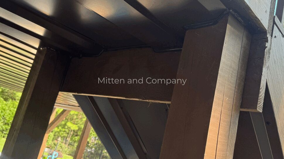Deck Underside Detail | Mitten & Company Close-up of dark-painted deck beams and soffit beside a home