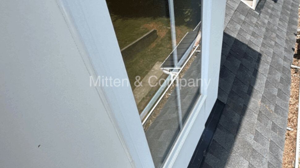 Dormer window with shingle roof and metal flashing from above.