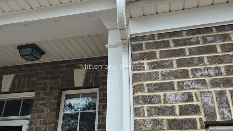White gutter and downspout on a brick home exterior
