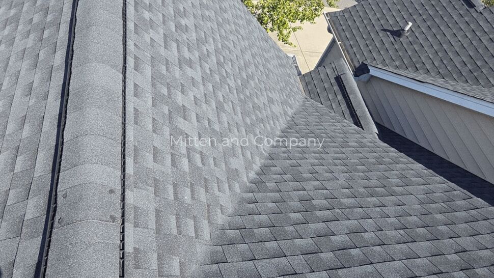Close view of a gray asphalt shingle roof with a finished ridge.