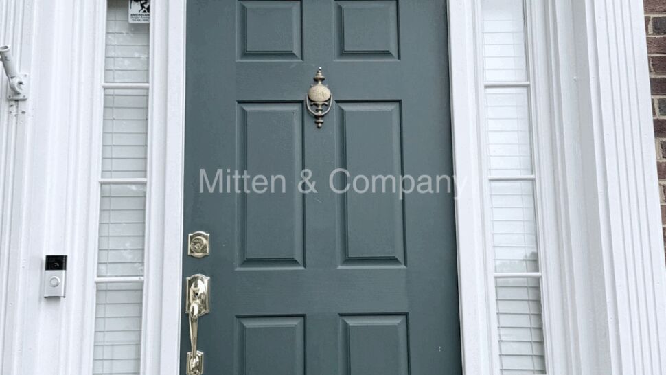 Green paneled front door with sidelights and brass hardware