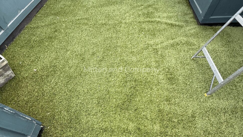 Rooftop turf with flashing details | Mitten & Company Overhead view of a rooftop covered with green turf and perimeter parapet walls and flashing.