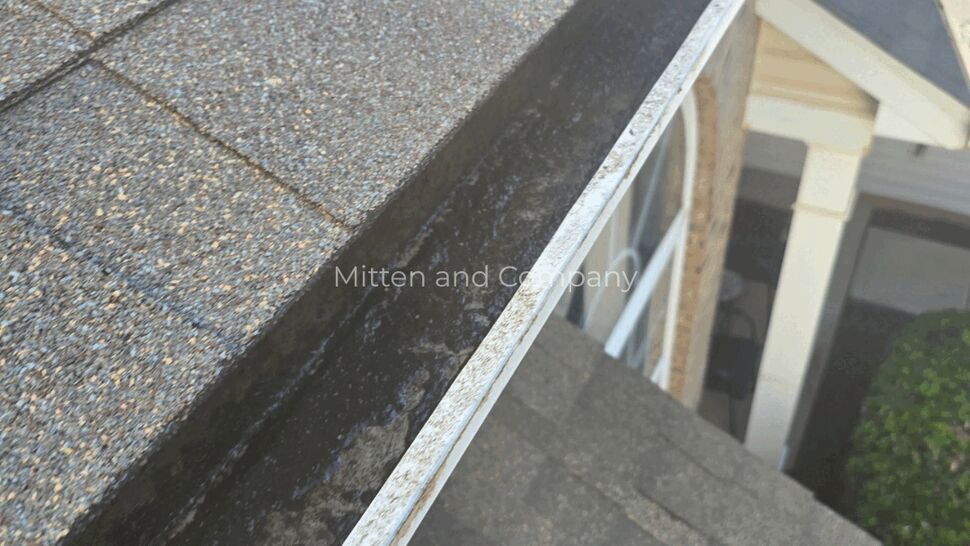 Close-up of gutter interior with blower nozzle clearing dirt
