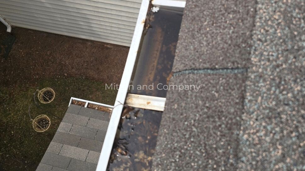 Gutter Corner Debris Check | Mitten & Company Leaf-filled gutter corner viewed from a residential roof