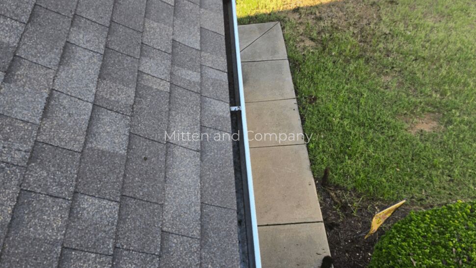 Roof edge and gutter with small debris and sidewalk below