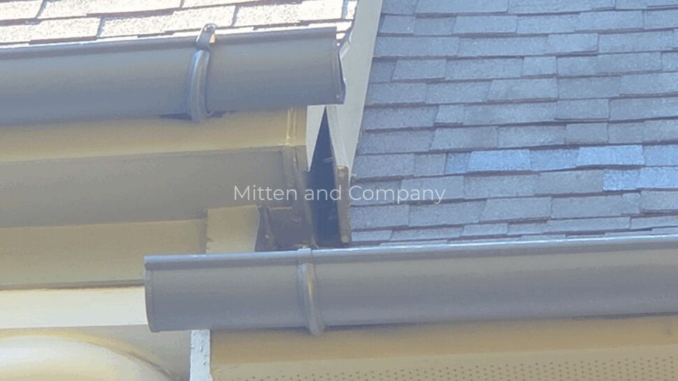 Close-up of gutter joints and roof valley flashing where two roof planes meet.