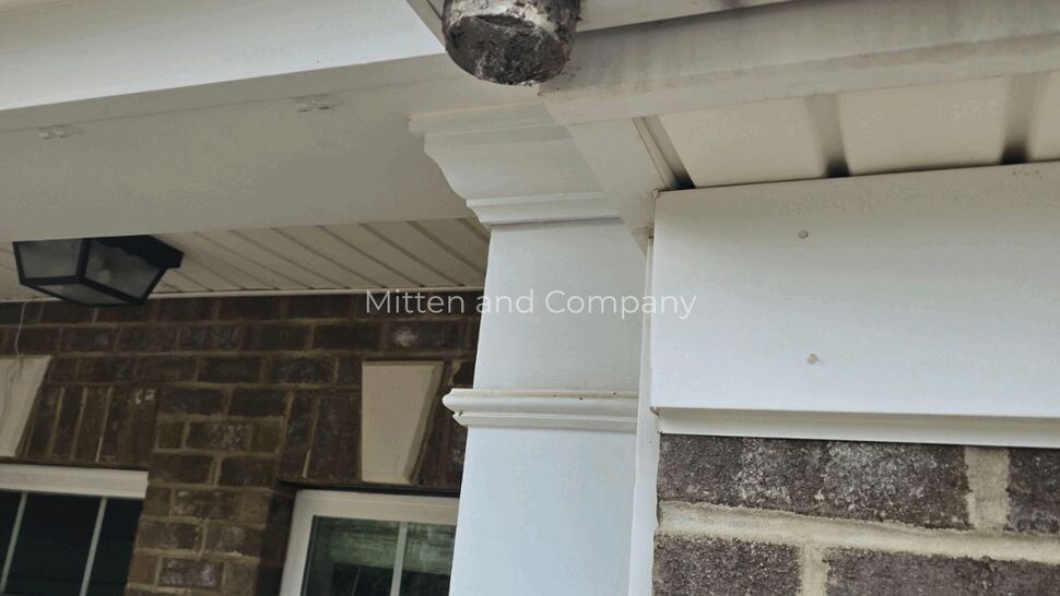 Close-up of a damaged gutter outlet beneath a roof edge