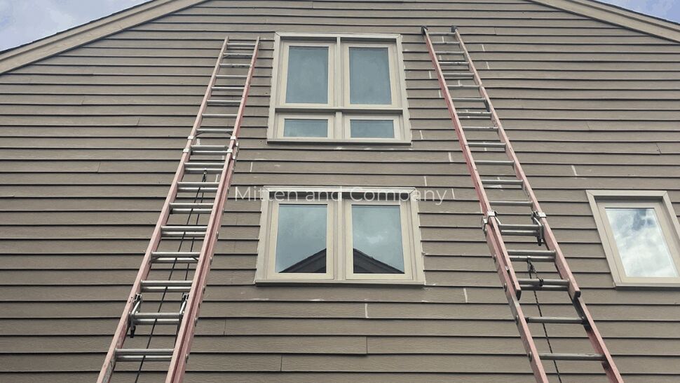 House Siding Ladder Access | Mitten & Company Ladders positioned against a house with horizontal siding and windows