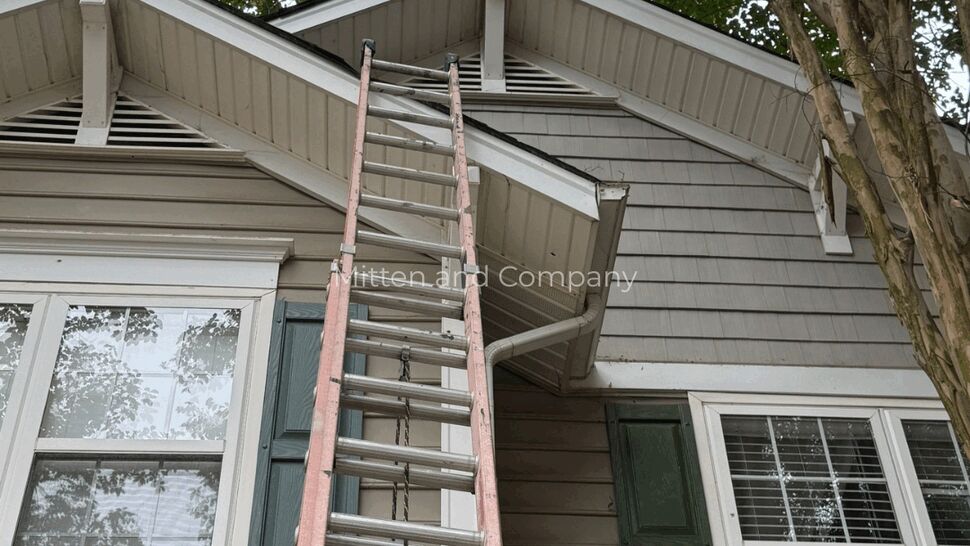 Tall ladder up to the gable inspecting shingles, soffit, and eaves on a townhouse