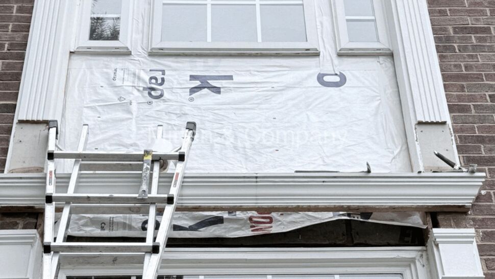 Extension ladder and power tools at front entry during repair