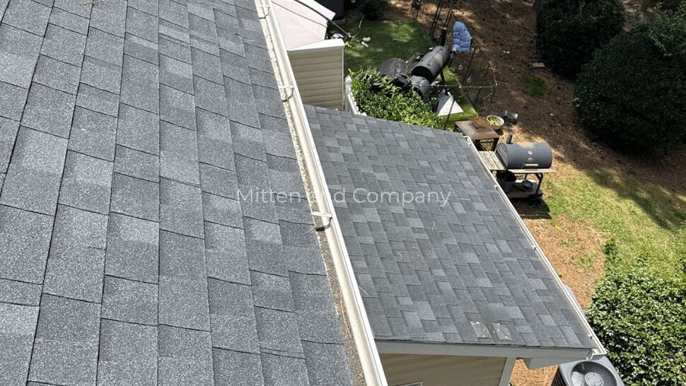 Long perspective of asphalt shingle roof and adjacent gutter running along eaves