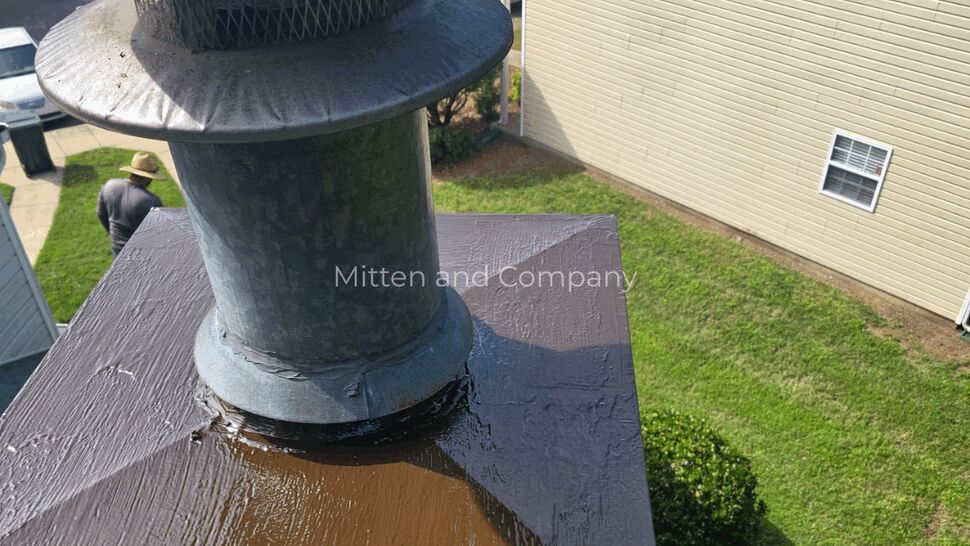Metal chimney cap with sealed crown | Mitten & Company Aerial view of a metal chimney cap and sealed crown on a shingled roof