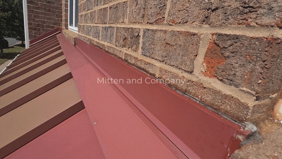 Metal Roof Wall Seam | Mitten & Company Red standing-seam metal roofing meets a brick exterior wall