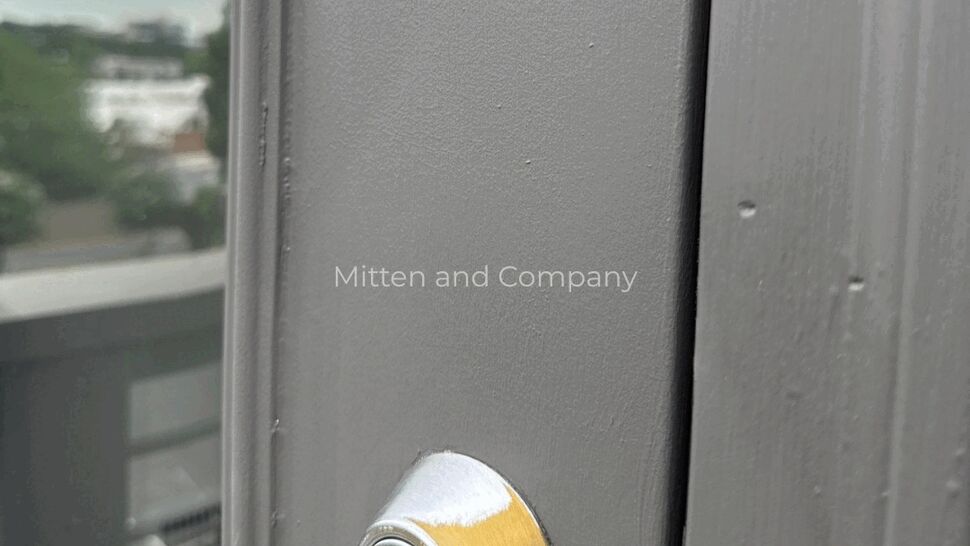 Exterior deadbolt on multifamily door | Mitten & Company Close-up of brass deadbolt and gray door trim on an exterior apartment door.