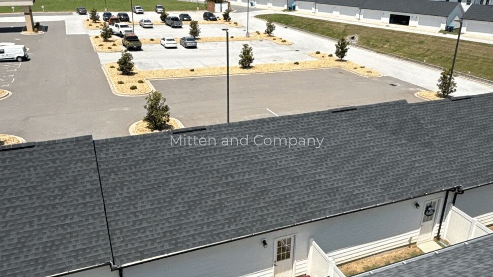 Aerial view of gray shingle roofs across a multifamily community.
