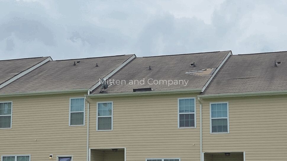 Multifamily rowhome roofing damage | Mitten & Company Beige multifamily rowhomes with missing shingles and roof damage on upper units