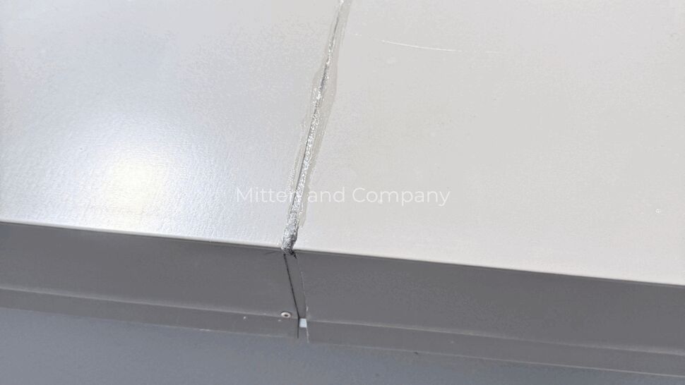 Parapet coping joint with sealant repair at rooftop edge.