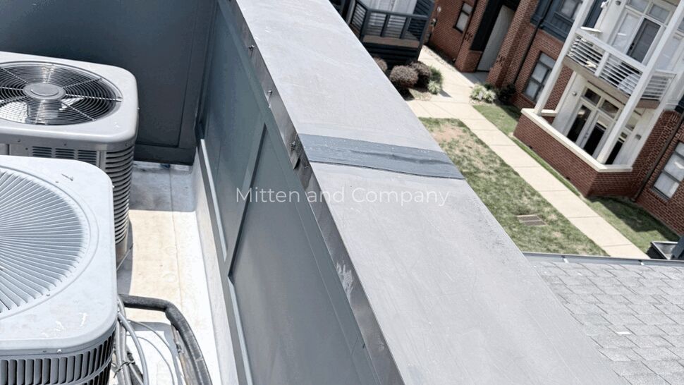 Parapet Storm Damage Repair | Mitten & Company Parapet cap with reinforced patch tape repair above residential courtyard