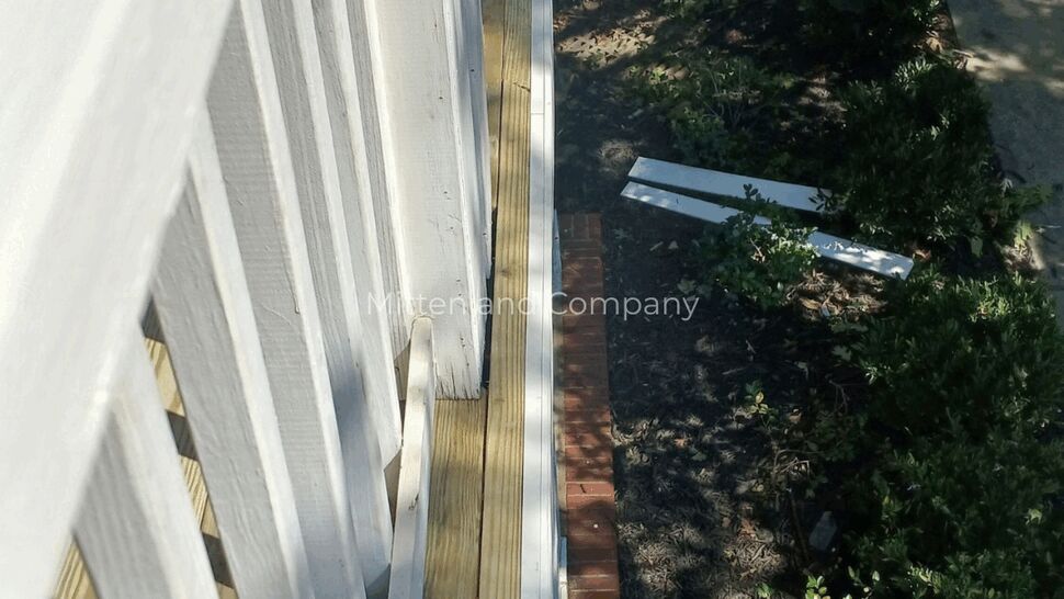 Porch Deck Side Repair | Mitten & Company Side view of white porch railing and new wood deck boards