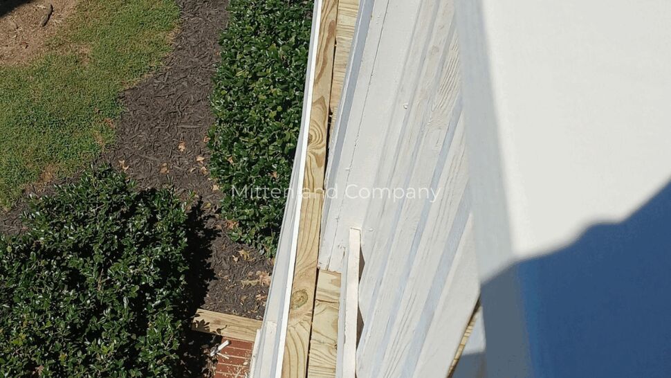 Porch Railing and Deck Edge | Mitten & Company White porch railing beside newly installed deck framing and landscaping