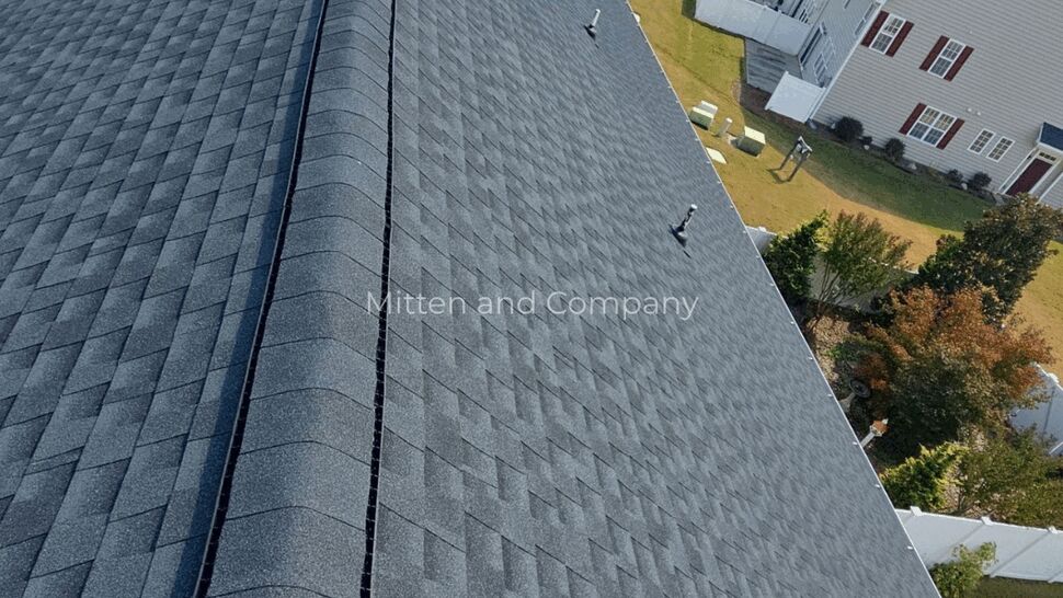 Aerial view of a gray shingle roof overlooking a residential neighborhood.