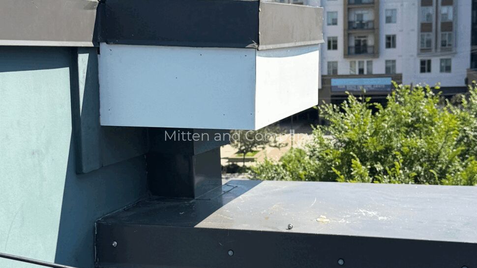 Corner roof detail with white fascia box and metal cap over parapet