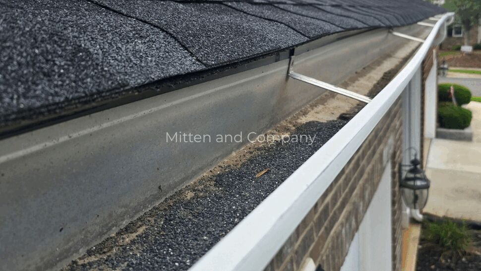 Black roof shingles above a long white gutter channel