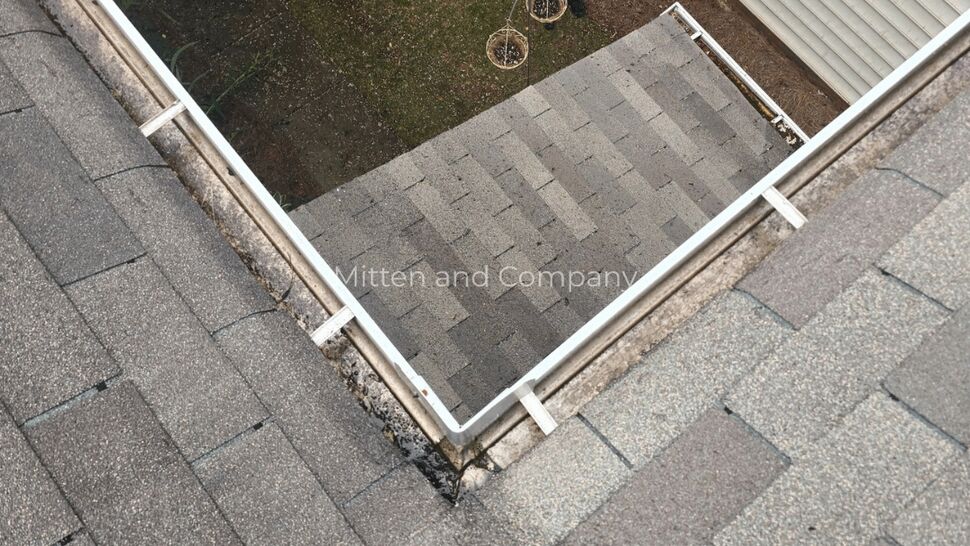 Roof and Gutter Inspection | Mitten & Company Roofer inspecting gray shingles and white gutters from above