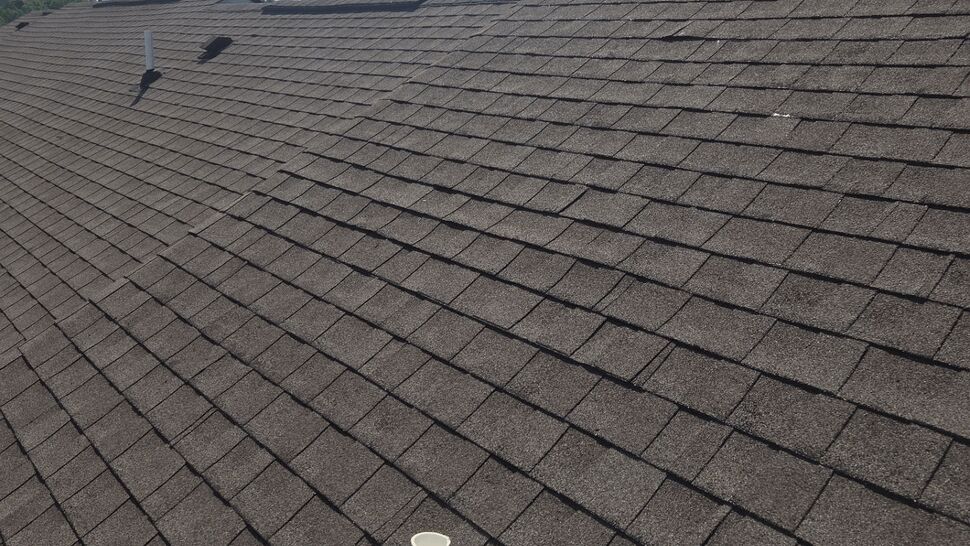 Close-up of asphalt shingle roof with a plumbing vent boot and clear sky