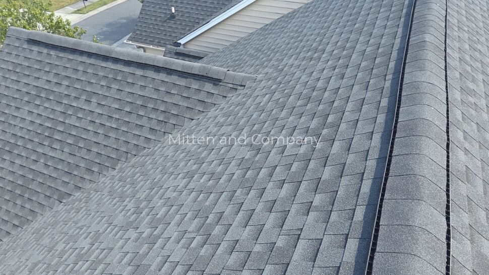 Gray shingles cover intersecting roof planes and a prominent roof valley.
