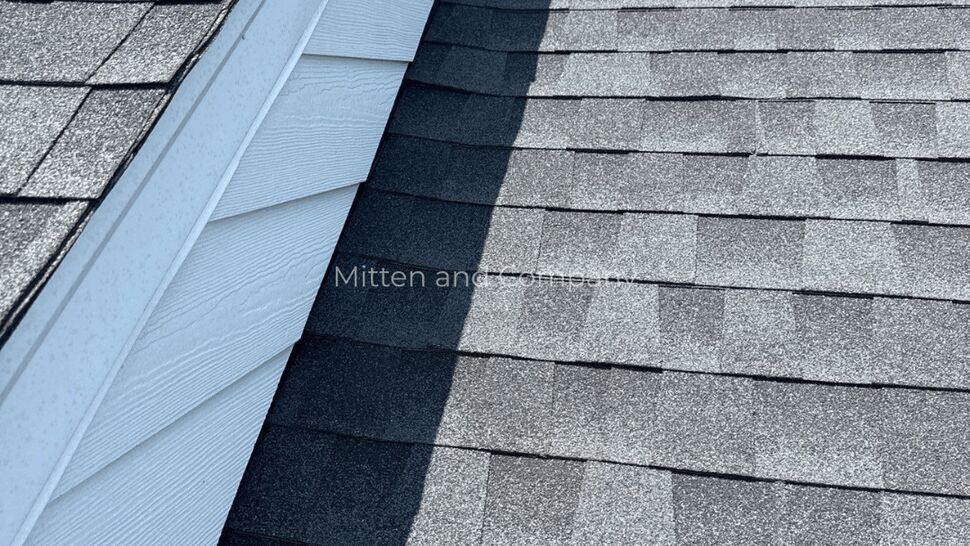 Gray shingles and white siding bordering a roof valley.