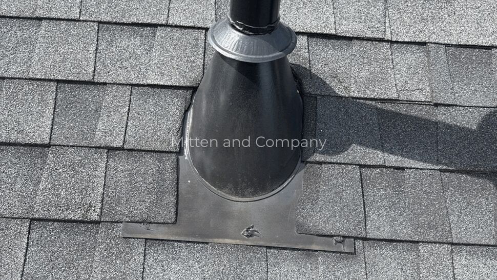 Close-up of black roof vent flashing on gray asphalt shingles.