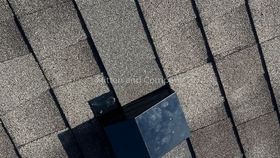 Close-up of a roof vent and metal flashing on gray asphalt shingles