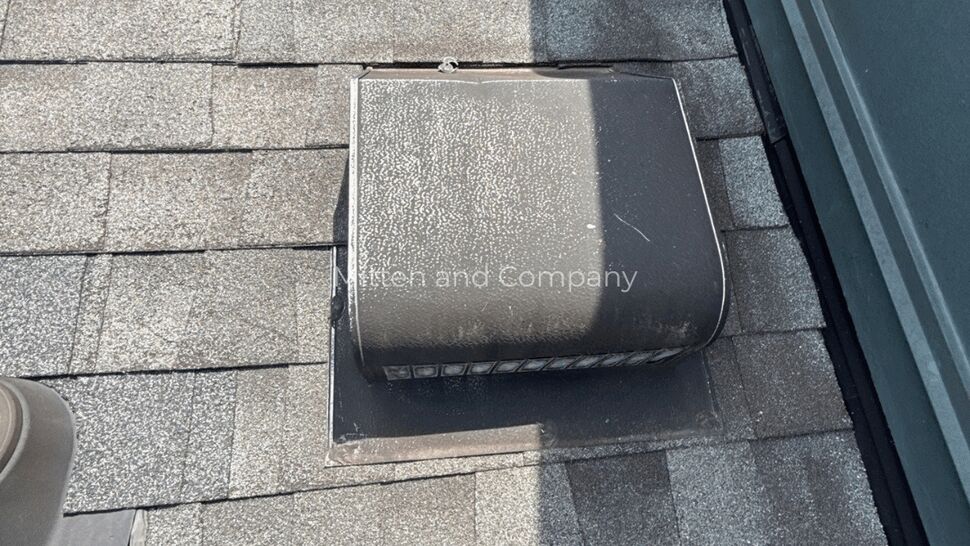 Roof vent and flashing detail | Mitten & Company Roof vent with metal housing and surrounding shingles near wall flashing.