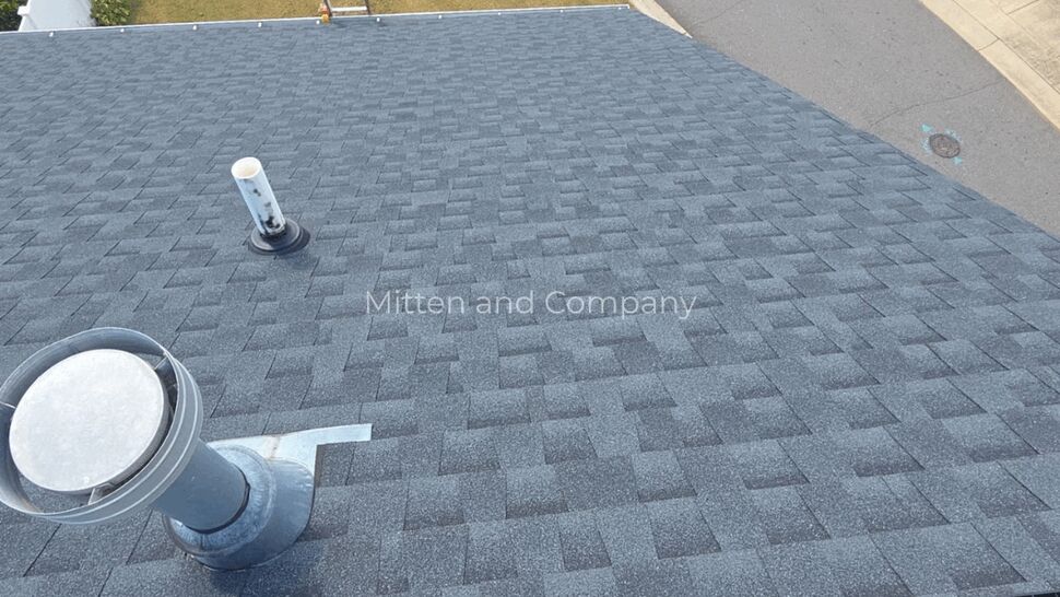Gray shingle roof with metal ventilation pipes and a roof edge.