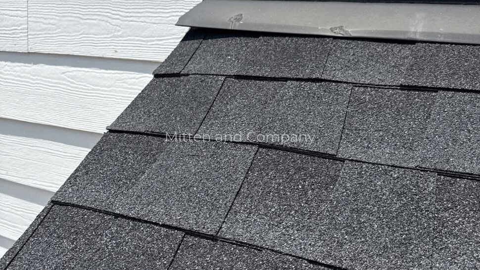 Close-up of shingles meeting white siding with metal flashing.
