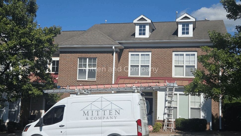 Mitten & Company van parked beside a brick home with a shingle roof