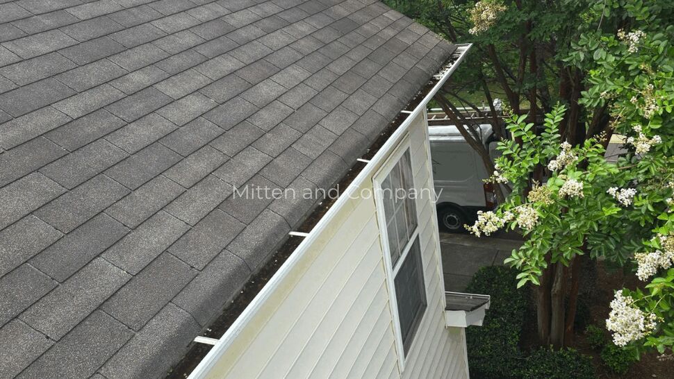 Roofline and Gutters | Mitten & Company Gray shingle roof and white gutter beside leafy trees