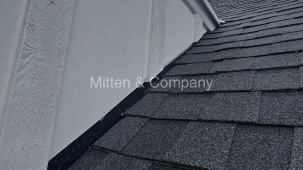 Shingle roof meeting wall with flashing at roofline
