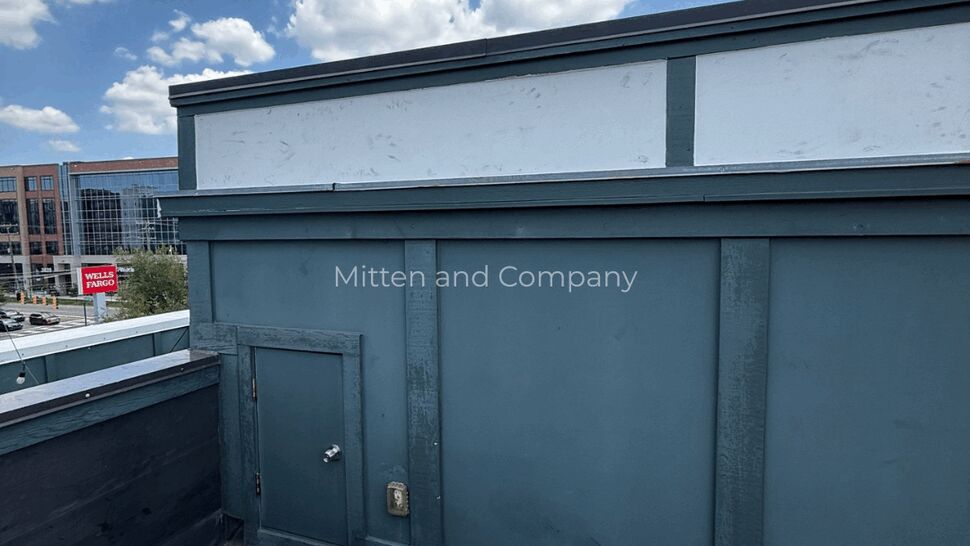 Rooftop access door with nearby HVAC unit and painted parapet wall