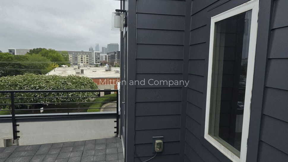 Rooftop Deck and Roofing Details | Mitten & Company Rooftop deck with railing and city skyline beyond, gray siding on facade.