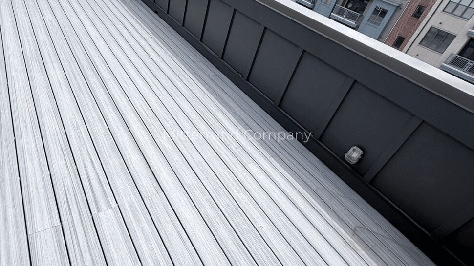 Flat Rooftop Deck and Parapet | Mitten & Company Flat rooftop deck with wood-look decking and metal parapet overlooking apartment buildings.