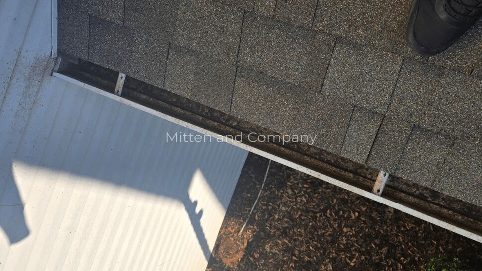 Top-down view of roof shingles and gutter edge over entryway