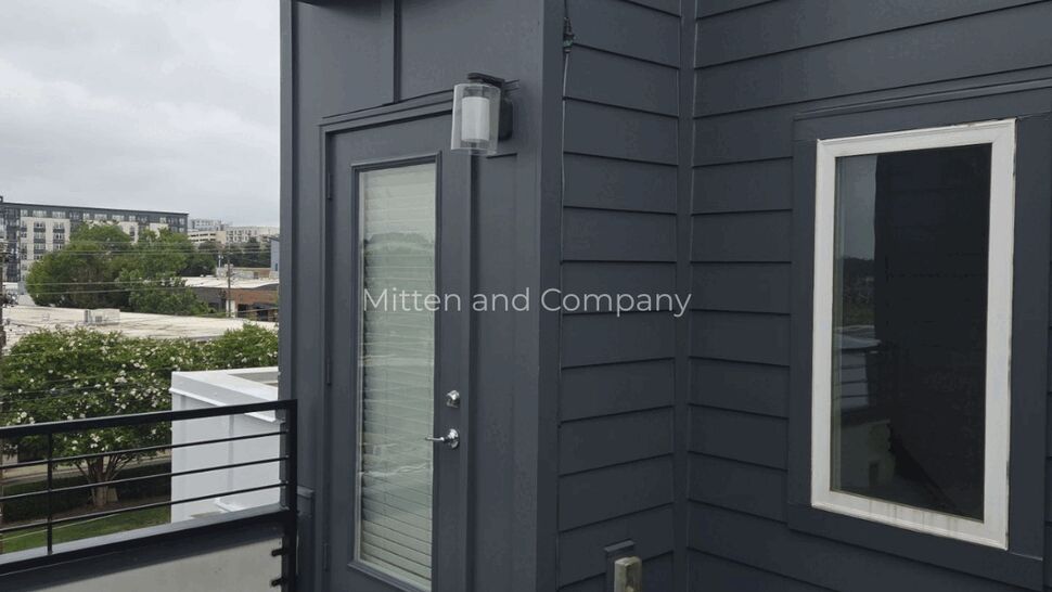 Penthouse Door with Gray Siding | Mitten & Company Rooftop penthouse door with gray siding, orange awning, and paver tiles.