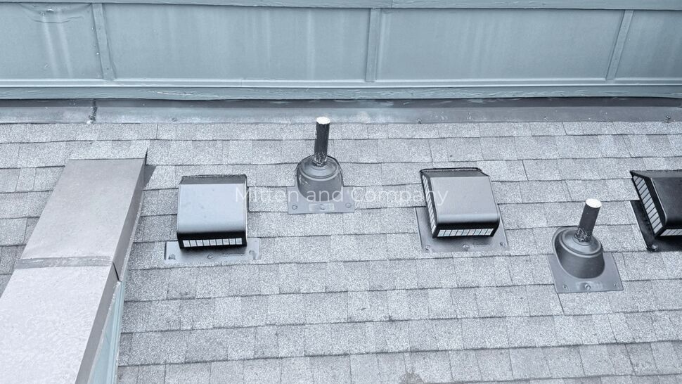 Aerial rooftop vents and parapet | Mitten & Company Aerial view of a shingled roof with multiple vents and a parapet.